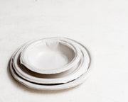     Handmade white stoneware dishes with irregular paper-like edges
* Contemporary stoneware tableware inspired by disposable paper plates
* Sculptural handmade ceramic dishes by Casa Retortillo
* Organic stoneware dish set photographed on neutral background
* Minimal handmade stoneware from the Arqueologies collection