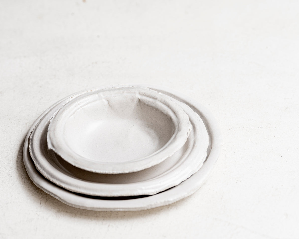     Handmade white stoneware dishes with irregular paper-like edges
* Contemporary stoneware tableware inspired by disposable paper plates
* Sculptural handmade ceramic dishes by Casa Retortillo
* Organic stoneware dish set photographed on neutral background
* Minimal handmade stoneware from the Arqueologies collection
