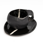     Handmade black stoneware coffee cup and saucer with white line detail.