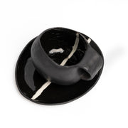     Handmade black stoneware coffee cup and saucer with white line detail.