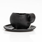     Handmade black stoneware coffee cup and saucer with white line detail.