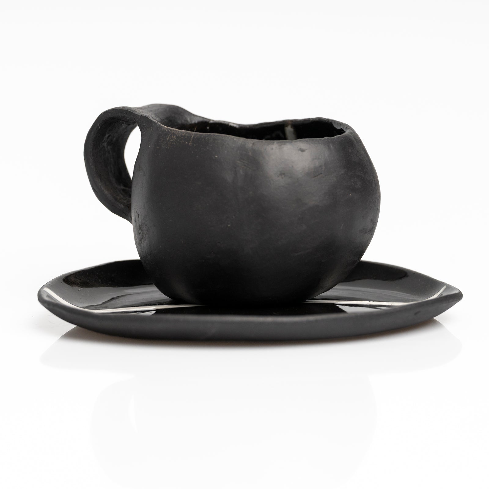     Handmade black stoneware coffee cup and saucer with white line detail.