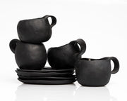     Handmade black stoneware coffee cups and saucers with white line detail.