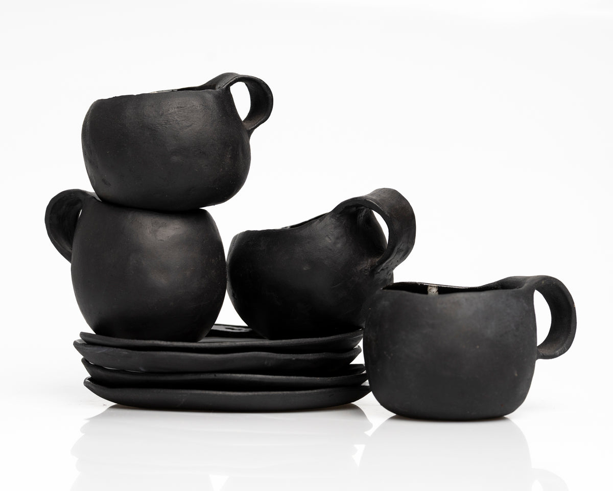     Handmade black stoneware coffee cups and saucers with white line detail.