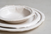     Handmade white stoneware dishes with irregular paper-like edges
* Contemporary stoneware tableware inspired by disposable paper plates
* Sculptural handmade ceramic dishes by Casa Retortillo
* Organic stoneware dish set photographed on neutral background
* Minimal handmade stoneware from the Arqueologies collection