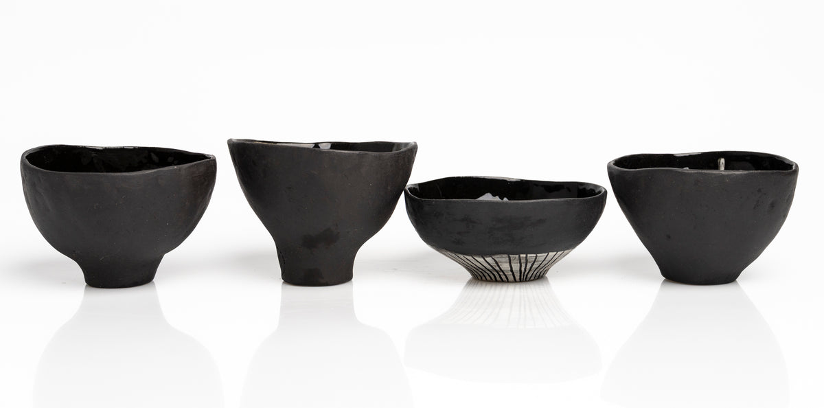     Handmade black stoneware snack bowls with unique hand-painted interiors.