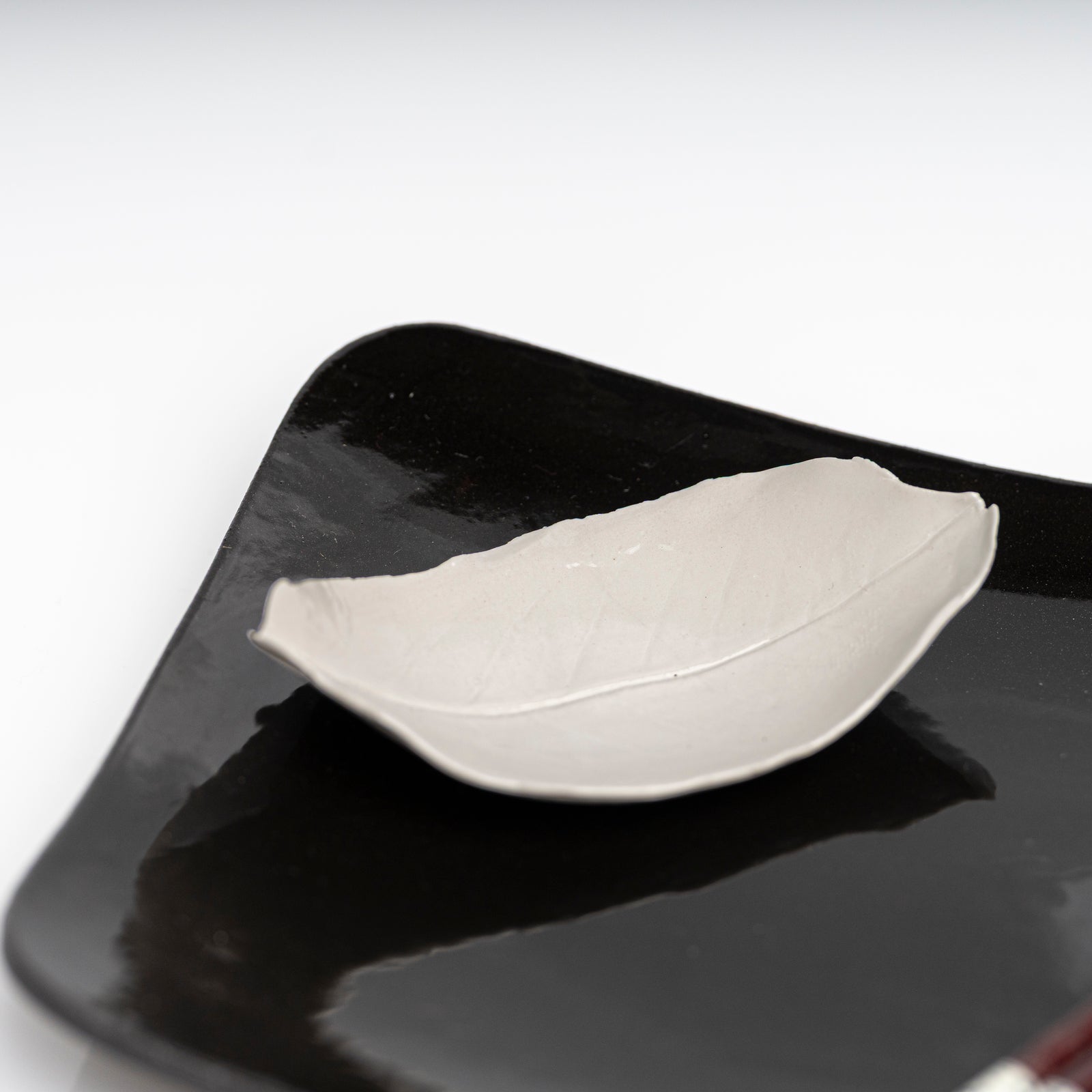     Handmade porcelain leaf dish with glossy white glaze.
